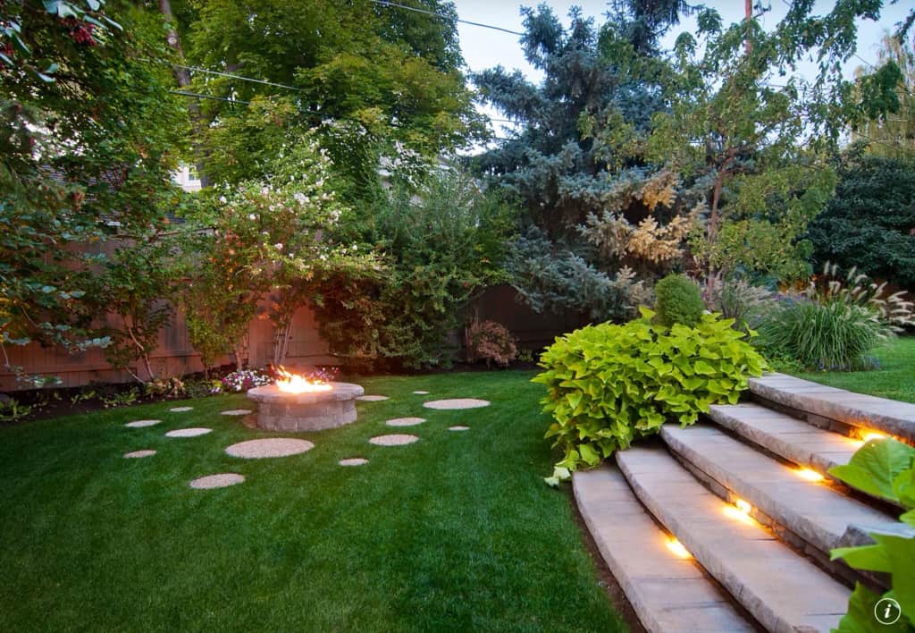A charming landscape backyard with firepit and lighted stairway