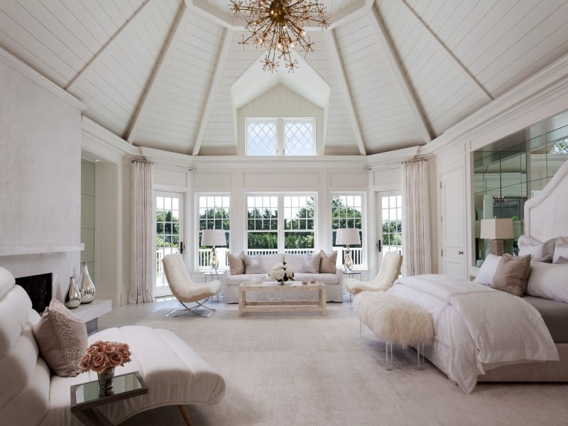 All white master bedroom with exposed wood ceiling