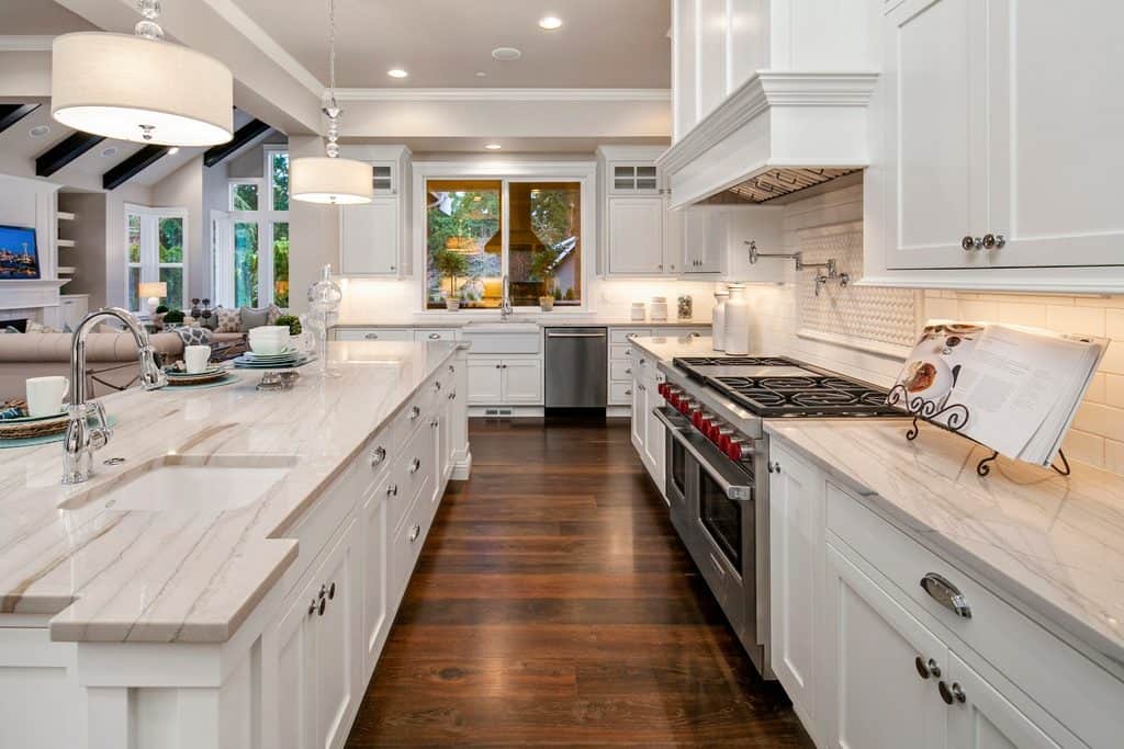 custom white kitchen with marble countertops, subway tile backsplash, hickory solid wideplank flooring