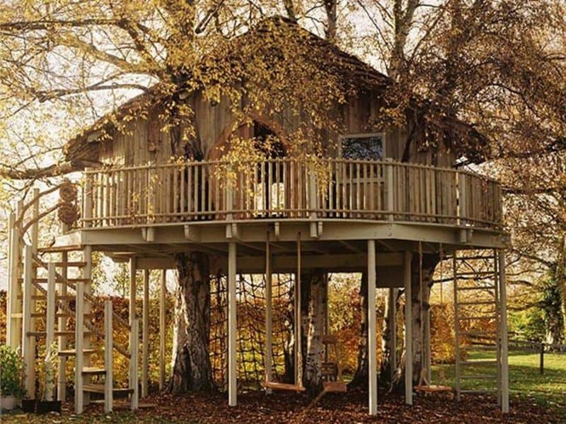 large wooden tree house with fence