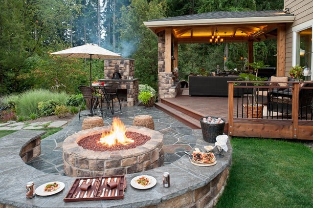Traditional flagstone back yard patio design with fire pit thats attached to a deck